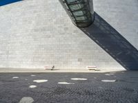 a building made out of white bricks has some white chairs in it next to a concrete wall