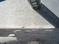 a building made out of white bricks has some white chairs in it next to a concrete wall