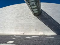 a building made out of white bricks has some white chairs in it next to a concrete wall