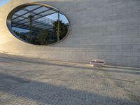 a building that has windows and a bench in front of it and reflection on the glass of the window