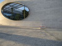 a building that has windows and a bench in front of it and reflection on the glass of the window