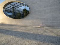 a building that has windows and a bench in front of it and reflection on the glass of the window