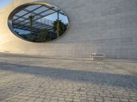 a building that has windows and a bench in front of it and reflection on the glass of the window