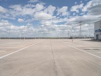 a parking lot has an empty and dry looking area with white clouds in the blue sky