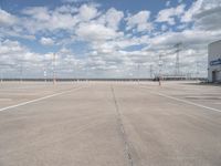 a parking lot has an empty and dry looking area with white clouds in the blue sky