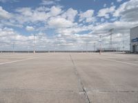 a parking lot has an empty and dry looking area with white clouds in the blue sky