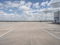 a parking lot has an empty and dry looking area with white clouds in the blue sky