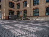 a brick courtyard has steps leading up to it, and a blue umbrella is on the ground