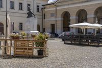 a courtyard and courtyard of an european building with lots of tables and umbrellas and benches