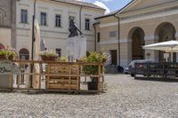 a courtyard and courtyard of an european building with lots of tables and umbrellas and benches