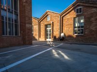 the shadow of a person walking past brick buildings in the sunlight near a bicycle lane