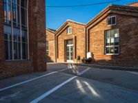 the shadow of a person walking past brick buildings in the sunlight near a bicycle lane