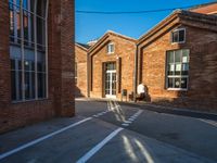 the shadow of a person walking past brick buildings in the sunlight near a bicycle lane