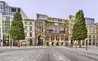 a building that has many different levels of windows and a parking area with bicycles on the cobblestones