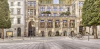 a building that has many different levels of windows and a parking area with bicycles on the cobblestones