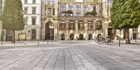 a building that has many different levels of windows and a parking area with bicycles on the cobblestones