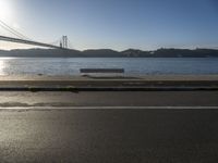 a woman running past the san francisco bridge at sunrise as the sun comes up over the bay