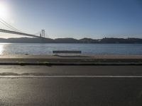 a woman running past the san francisco bridge at sunrise as the sun comes up over the bay