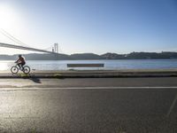 a woman running past the san francisco bridge at sunrise as the sun comes up over the bay