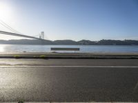 a woman running past the san francisco bridge at sunrise as the sun comes up over the bay