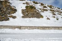 a skier in the mountains skis under a ramp with rocks on it and grass growing on the side