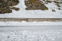 a skier in the mountains skis under a ramp with rocks on it and grass growing on the side