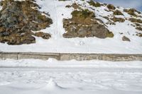 a skier in the mountains skis under a ramp with rocks on it and grass growing on the side