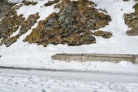 a skier in the mountains skis under a ramp with rocks on it and grass growing on the side