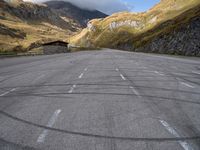 an empty car parking lot in front of mountains with clouds and a mountain view behind it