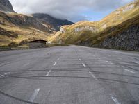 an empty car parking lot in front of mountains with clouds and a mountain view behind it