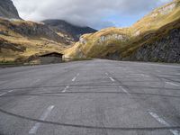 an empty car parking lot in front of mountains with clouds and a mountain view behind it