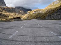 an empty car parking lot in front of mountains with clouds and a mountain view behind it