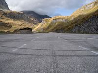 an empty car parking lot in front of mountains with clouds and a mountain view behind it