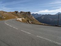 a man on a motorcycle that is going down a mountain road on a slope near the side