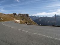 a man on a motorcycle that is going down a mountain road on a slope near the side