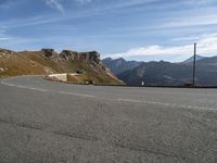 a man on a motorcycle that is going down a mountain road on a slope near the side