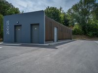 a metal building with a corrugated door in front of it and trees lining the street behind it