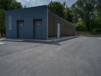 a metal building with a corrugated door in front of it and trees lining the street behind it