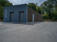 a metal building with a corrugated door in front of it and trees lining the street behind it