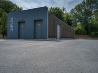 a metal building with a corrugated door in front of it and trees lining the street behind it