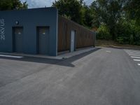 a metal building with a corrugated door in front of it and trees lining the street behind it