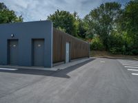 a metal building with a corrugated door in front of it and trees lining the street behind it