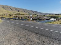 a long mountain road next to the sea and water falls below it in iceland, with sheep grazing near the bridge