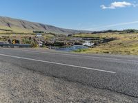 a long mountain road next to the sea and water falls below it in iceland, with sheep grazing near the bridge