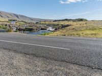 a long mountain road next to the sea and water falls below it in iceland, with sheep grazing near the bridge