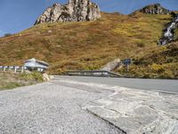 a curved mountain road with a waterfall coming down the side of it and a stop sign on the side