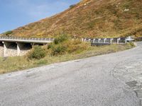 a person riding a skateboard down the side of a mountain road with a paved slope behind