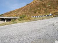 a person riding a skateboard down the side of a mountain road with a paved slope behind