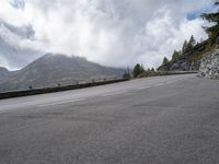 a person on a bike riding along the highway under a cloudy sky with mountains behind them