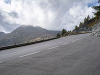 a person on a bike riding along the highway under a cloudy sky with mountains behind them